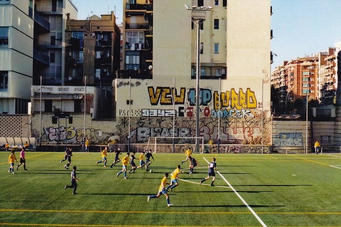Young men playing football on an inner city pitch in Barcelona